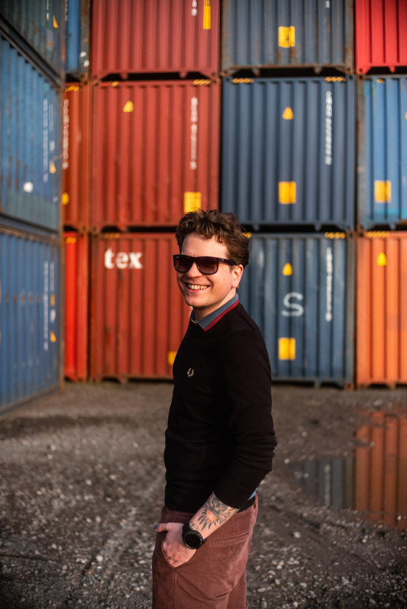 Felix Bundschuh vor Containern mit Sonnenbrille, Produktionskoordination bei WE ARE PRODUCERS. Credit: Fabian Riediger